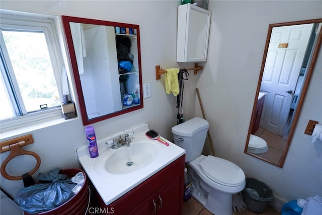 bathroom featuring vanity, toilet, a healthy amount of sunlight, and tile patterned flooring