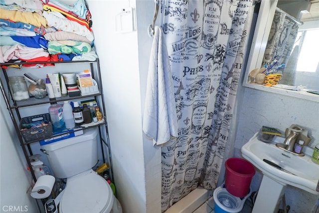 bathroom featuring toilet, walk in shower, and sink