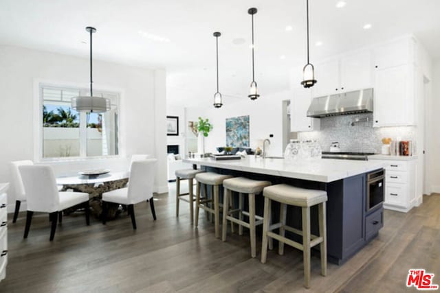 kitchen with white cabinetry, pendant lighting, dark hardwood / wood-style floors, and a kitchen breakfast bar