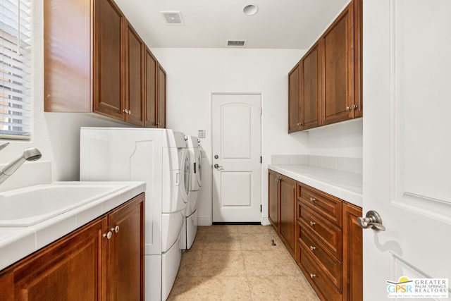 clothes washing area featuring cabinets, light tile patterned flooring, sink, and washing machine and clothes dryer