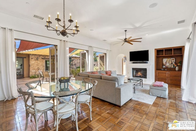 living room featuring parquet flooring and ceiling fan with notable chandelier