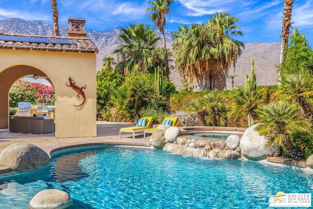 view of swimming pool with an in ground hot tub, a mountain view, and a patio