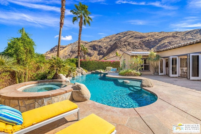 view of swimming pool with an in ground hot tub, a mountain view, and a patio area