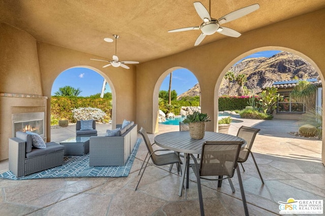 view of patio / terrace with a mountain view, an outdoor living space with a fireplace, and ceiling fan