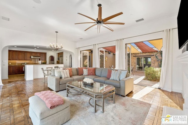 tiled living room with ceiling fan with notable chandelier