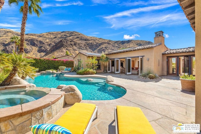 view of pool featuring an in ground hot tub, a mountain view, and a patio