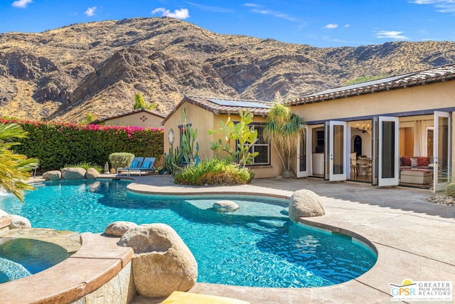 view of swimming pool featuring a patio area, a mountain view, and an in ground hot tub