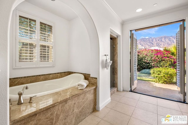 bathroom featuring a mountain view, a relaxing tiled tub, ornamental molding, and tile patterned flooring