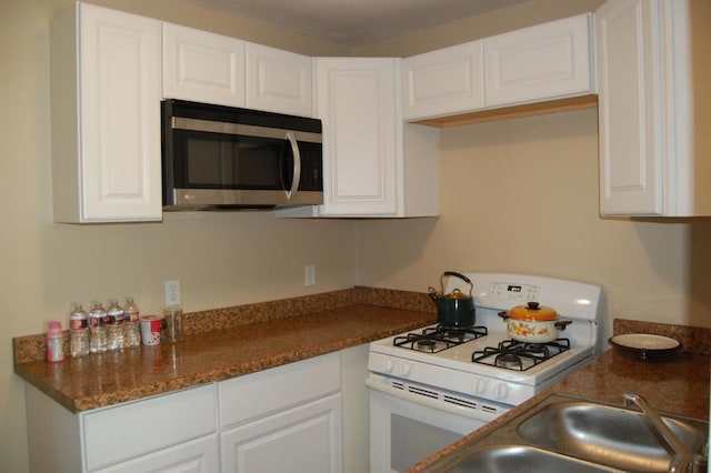 kitchen featuring white cabinets, white gas stove, and sink