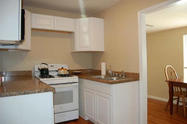 kitchen featuring hardwood / wood-style floors, white cabinetry, white gas range, and sink