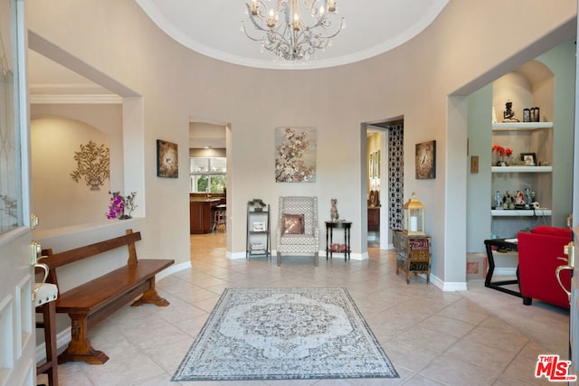 entryway featuring a high ceiling, light tile patterned floors, an inviting chandelier, and crown molding