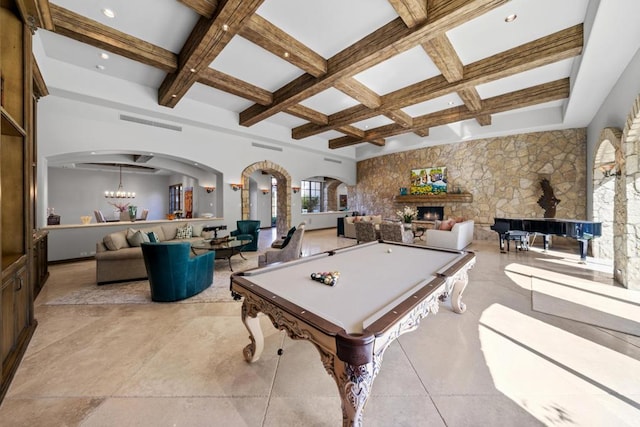 rec room featuring coffered ceiling, pool table, a stone fireplace, beam ceiling, and a notable chandelier