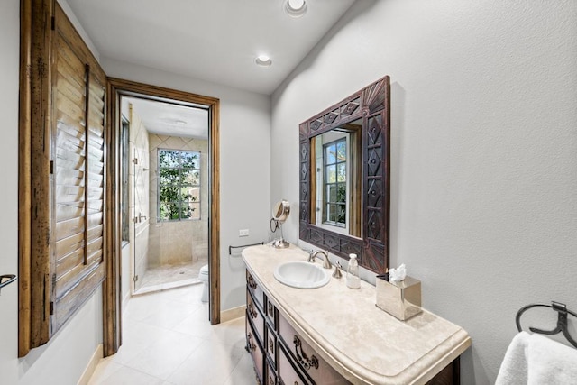 bathroom with a wealth of natural light, vanity, a tile shower, and toilet