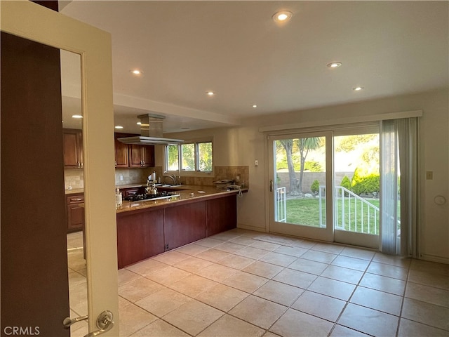 kitchen featuring decorative backsplash, kitchen peninsula, and light tile patterned floors