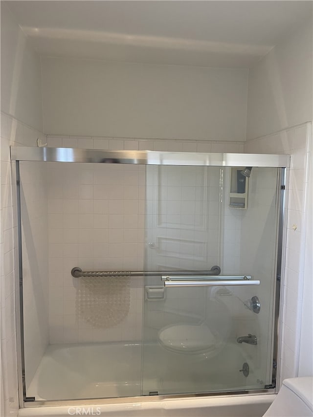 bathroom featuring bath / shower combo with glass door and toilet