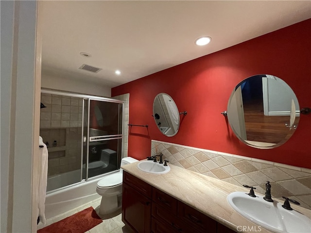 full bathroom featuring tasteful backsplash, shower / bath combination with glass door, toilet, tile patterned floors, and vanity