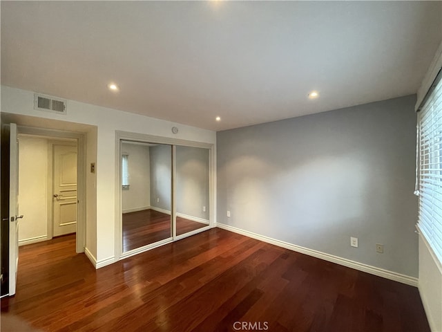 unfurnished bedroom featuring baseboards, visible vents, wood finished floors, and a closet