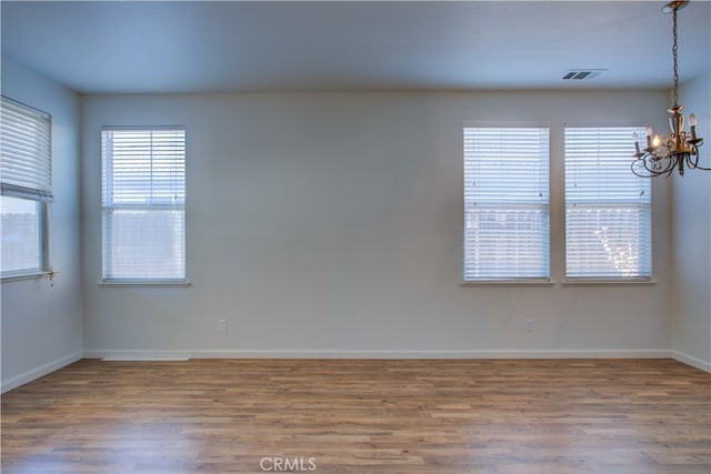 spare room with a notable chandelier and hardwood / wood-style floors