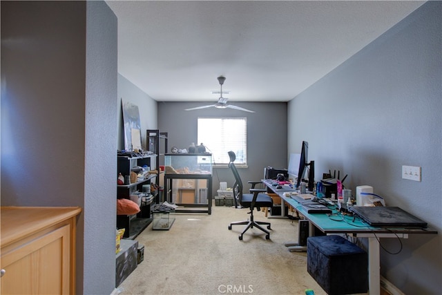 carpeted home office featuring ceiling fan