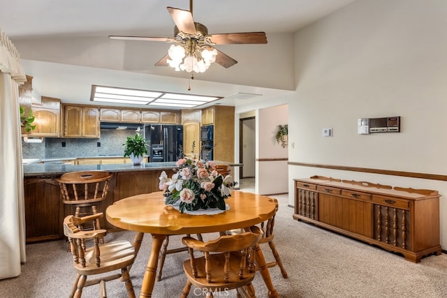 carpeted dining room featuring ceiling fan and vaulted ceiling