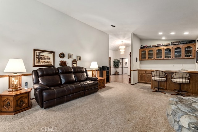 living room with lofted ceiling, a chandelier, light colored carpet, and wet bar