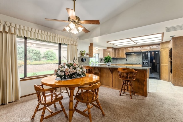 carpeted dining room featuring ceiling fan and vaulted ceiling