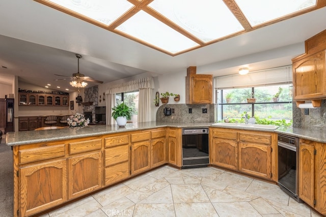 kitchen featuring black dishwasher, decorative backsplash, sink, and kitchen peninsula