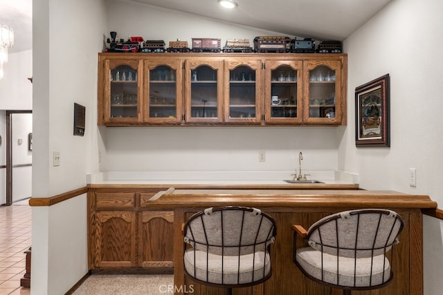 bar with lofted ceiling, sink, and light tile patterned floors