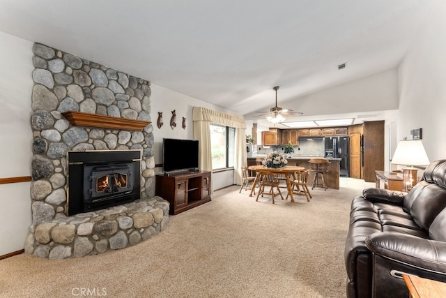 living room featuring ceiling fan, light colored carpet, a fireplace, and vaulted ceiling