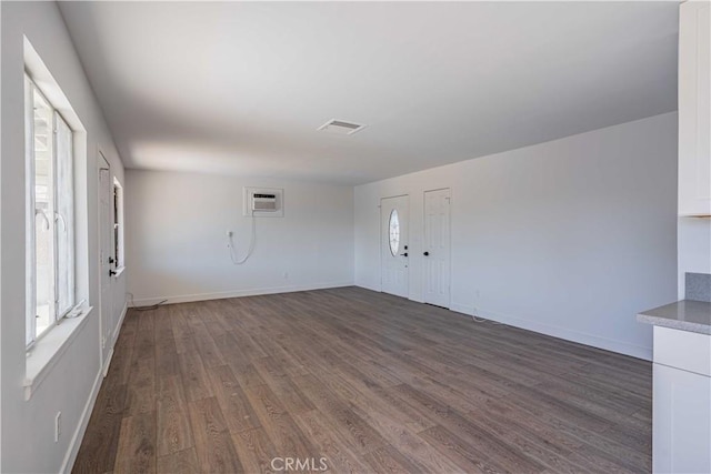 unfurnished room with a wall unit AC and dark hardwood / wood-style flooring