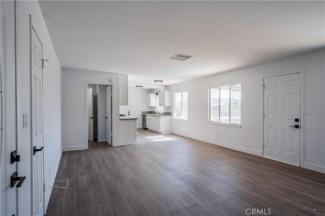 unfurnished living room featuring sink and dark hardwood / wood-style floors