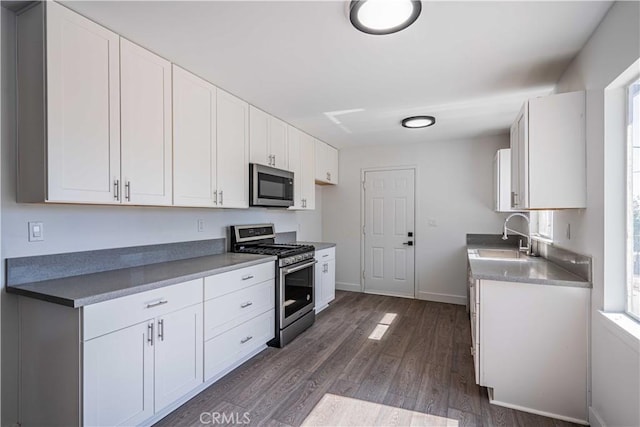 kitchen with sink, dark hardwood / wood-style flooring, white cabinets, and appliances with stainless steel finishes