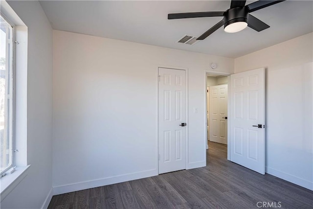 unfurnished bedroom with ceiling fan, dark hardwood / wood-style flooring, and a closet