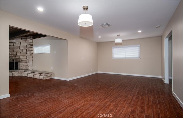 unfurnished room with dark hardwood / wood-style floors and a stone fireplace