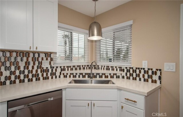 kitchen featuring white cabinetry, dishwasher, hanging light fixtures, and sink