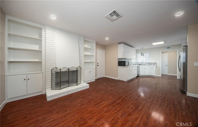 unfurnished living room featuring a brick fireplace and dark hardwood / wood-style floors