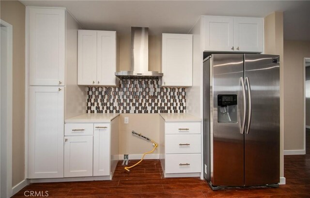 kitchen featuring stainless steel fridge, dark hardwood / wood-style floors, backsplash, wall chimney range hood, and white cabinets