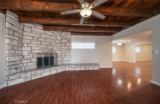 unfurnished living room featuring beam ceiling, a stone fireplace, and wooden ceiling