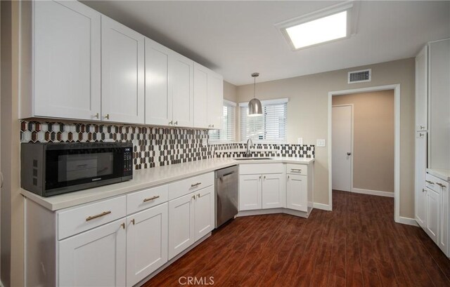 kitchen featuring backsplash, dishwasher, sink, white cabinetry, and hanging light fixtures