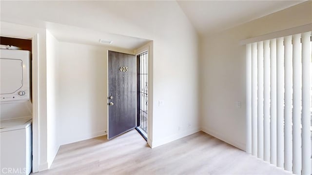 interior space with stacked washer and dryer and light hardwood / wood-style floors