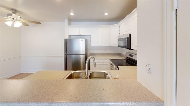 kitchen featuring appliances with stainless steel finishes, kitchen peninsula, white cabinets, and sink