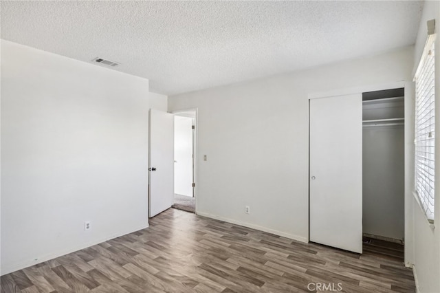 unfurnished bedroom featuring a closet, hardwood / wood-style flooring, and a textured ceiling