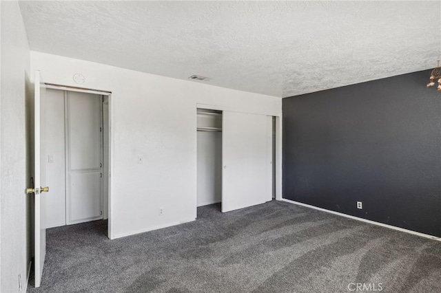 unfurnished bedroom featuring dark colored carpet, a textured ceiling, and a closet