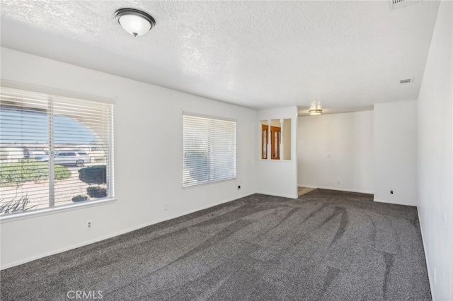 carpeted empty room featuring a textured ceiling