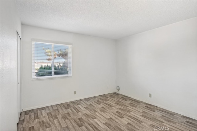 spare room with light hardwood / wood-style flooring and a textured ceiling