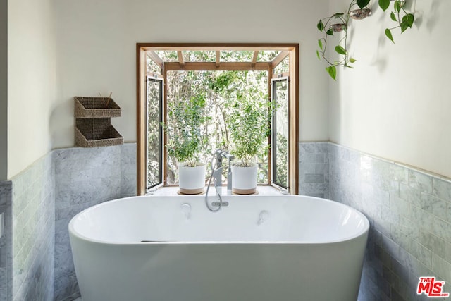 bathroom with a bath and tile walls