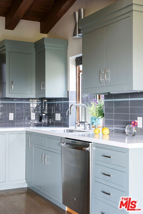 kitchen featuring decorative backsplash, stainless steel dishwasher, dark hardwood / wood-style flooring, beam ceiling, and sink