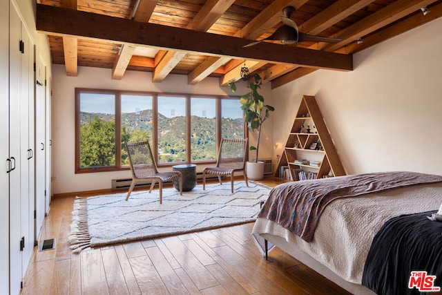 bedroom featuring beam ceiling, light wood-type flooring, wood ceiling, and a mountain view