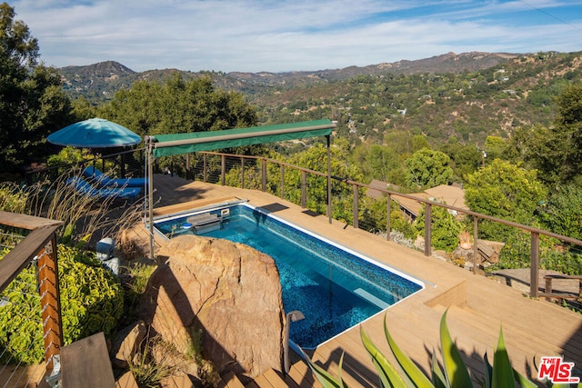 view of pool with a mountain view and a hot tub