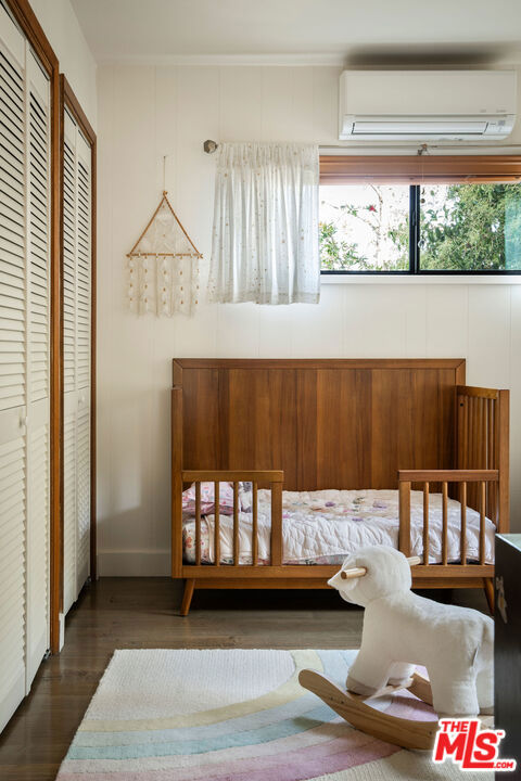 bedroom featuring a closet, dark hardwood / wood-style flooring, and a wall mounted AC